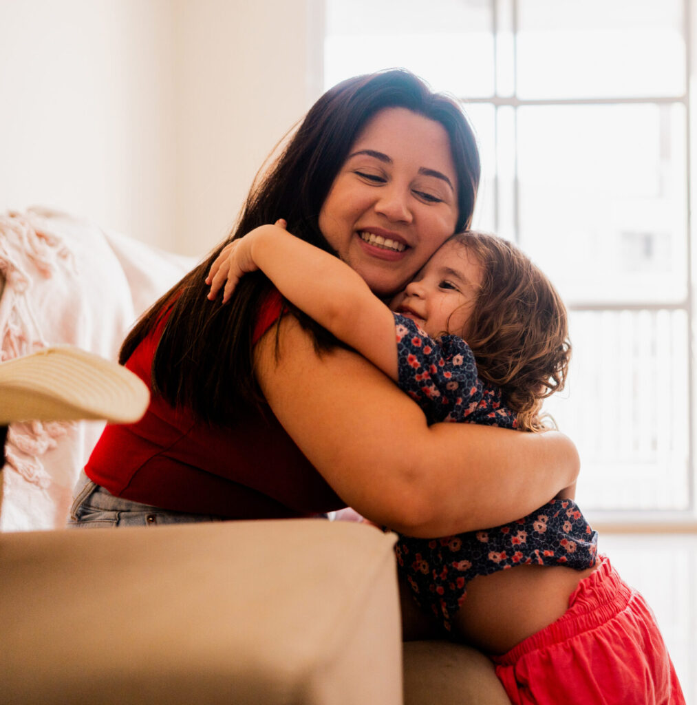 Mother embracing baby daughter at home
